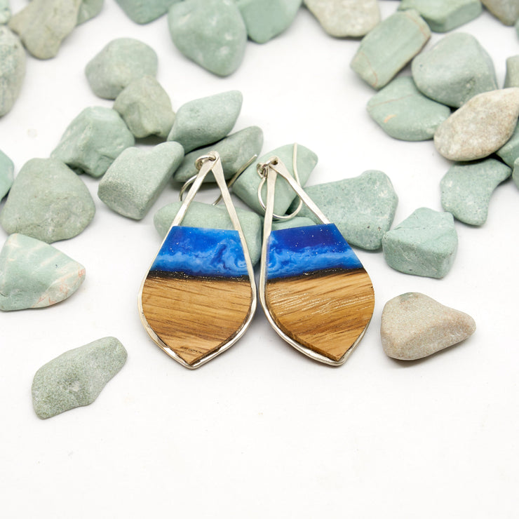 Branch and Barrel “Aurora” - Pointed Teardrop Bourbon Barrel Stave Earrings  Hand cut reclaimed oak bourbon barrel stave topped with a hand-tinted blue resin and framed in hand forged sterling-silver or 14k gold-fill.  Buy One, Plant One - One tree planted for every Branch+Barrel piece sold.